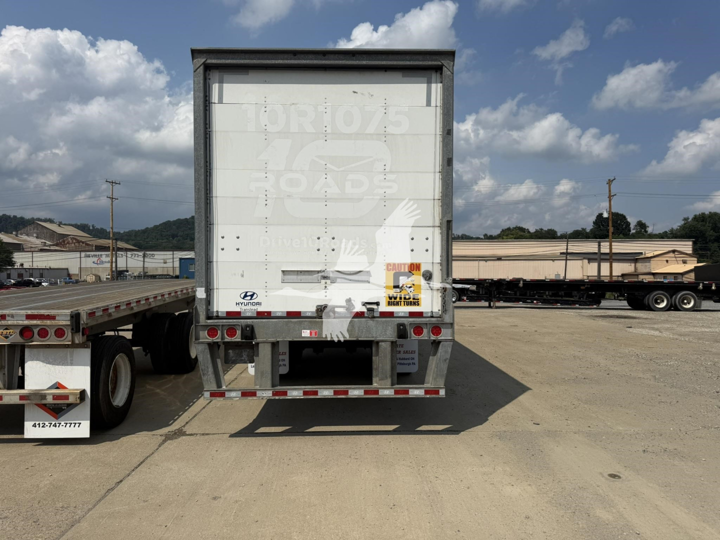 Rear view of Hyundai roll door trailer showing tail lights, bumper, and small decals with branding.
