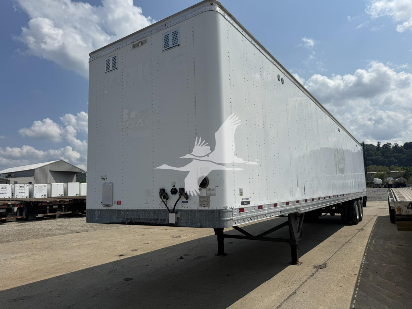 Trailer box showing raised landing gear and rear lighting on a Hyundai roll door van with a white logo of a flying bird on the side.