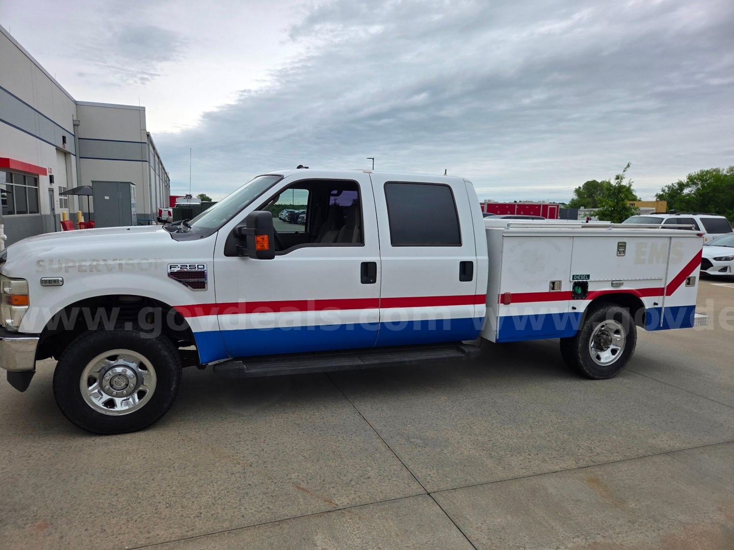 Ford F-250 service/utility truck with emergency vehicle livery, side compartments, large crew cab, dual rear wheels, long bed; white with blue and red stripe; running boards; stock number 558-272.