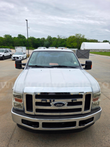 Ford F-250 front view showing chrome grille, bumper, fog lights, and dual side mirrors. Windshield with light tan sun visor header and vehicle badges visible.