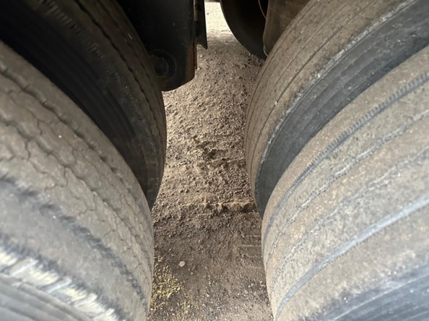 Two large rear tires of a 2020 Timpte Super Hopper trailer visible from between wheels; dirt on the ground between tires.