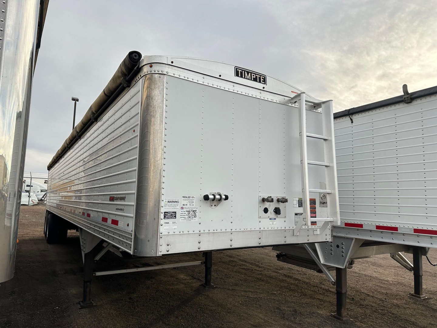 Timpte Super Hopper trailer showing side and rear with ladder, tongue jack, and rear discharge area.