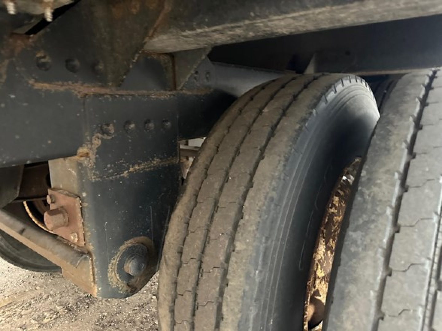 Trailer axle and dual tires on a 2020 Timpte Super Hopper showing wheel, suspension mount, and frame with dirt and rust-free surface.