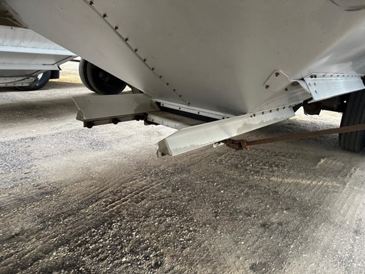 Timpte hopper trailer underside showing support brackets and mud/dirt on ground.