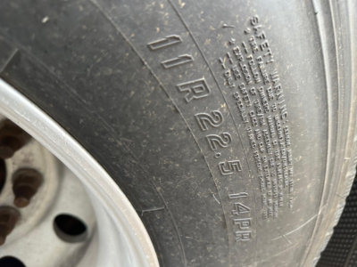 Tire sidewall with embossed tire size 10R22.5 and load rating 14PR on a trailer wheel.