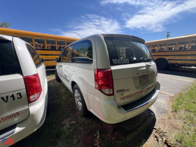 Dodge Grand Caravan minivan in a parking lot with yellow school buses in background, rear and side view.