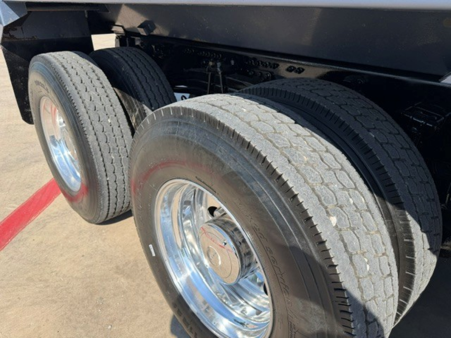 Truck rear dual wheels showing tires and chrome wheel rims under a dump truck bed.