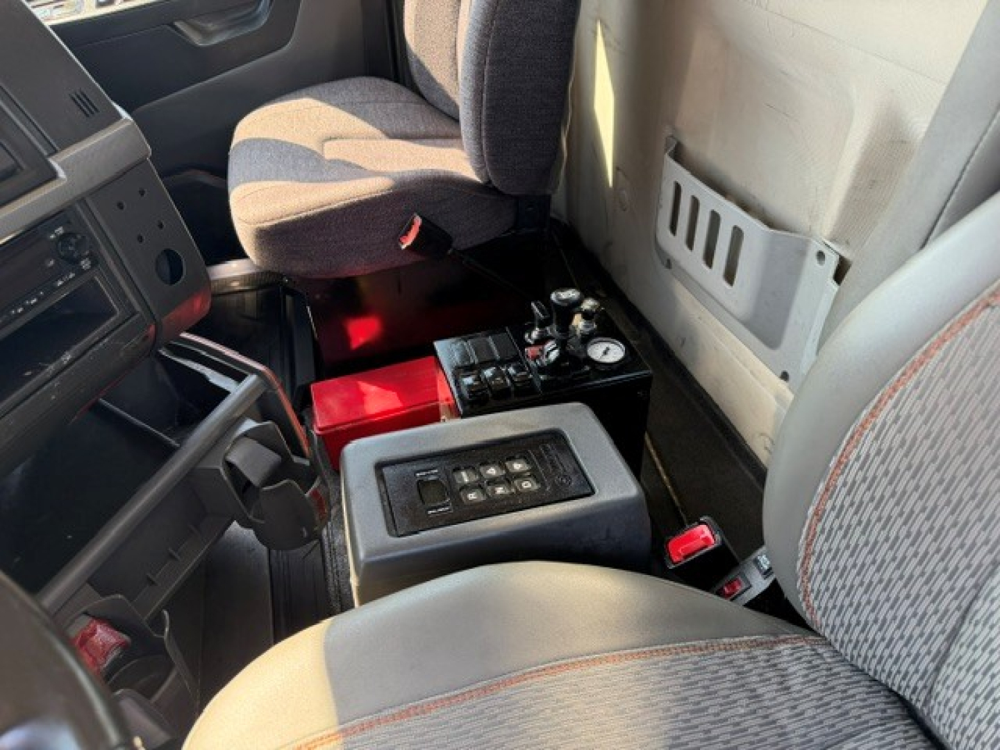 Volvo VHD truck interior showing center console with control panel and red battery box near seat