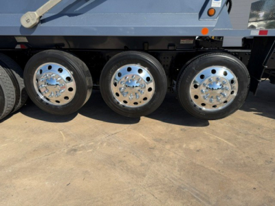 Three dual rear axles with polished chrome wheels on a Volvo dump truck. No legible text visible on the image.