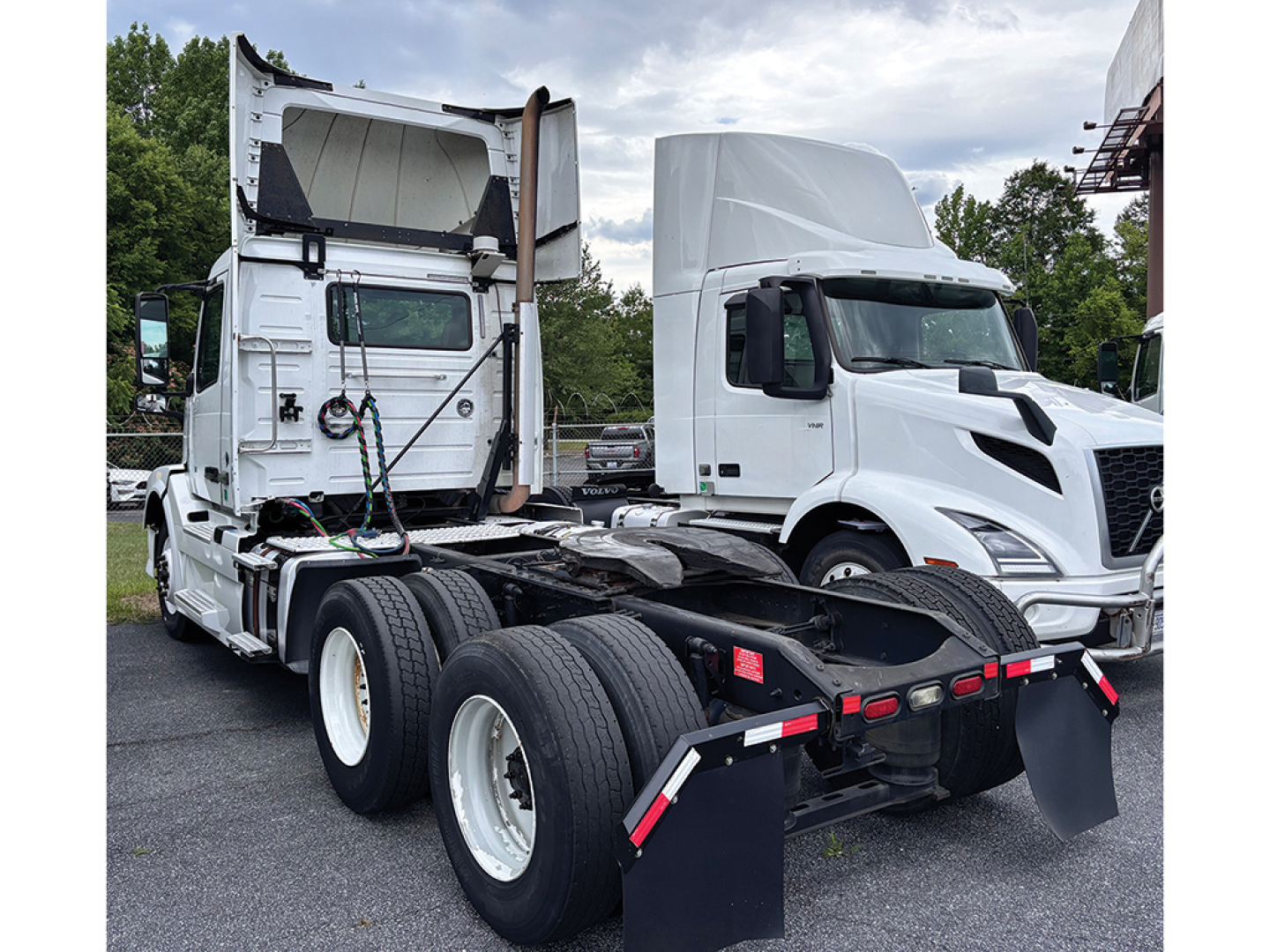 Volvo VNL 300 semi truck tractor rear view showing fifth-wheel and dual rear axles, white cab, sleeper in background, chassis with black components and tires.