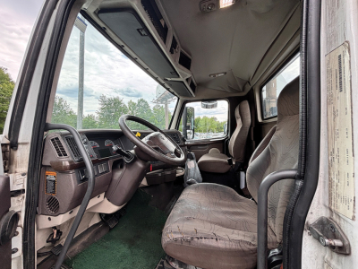Volvo VNL cab interior showing steering wheel, driver's seat, and dashboard in view from open door.