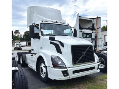 Truck cab showing Volvo VNL 300 with white exterior and raised sleeper, front grille, headlights, and dual rear wheels.