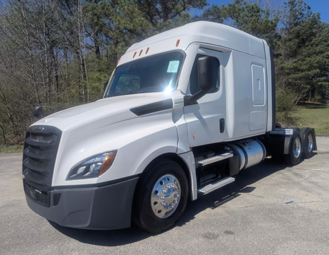 Freightliner Cascadia 126 sleeper cab tractor in white, side view showing front and midsection, with fuel tanks and dual rear axles.
