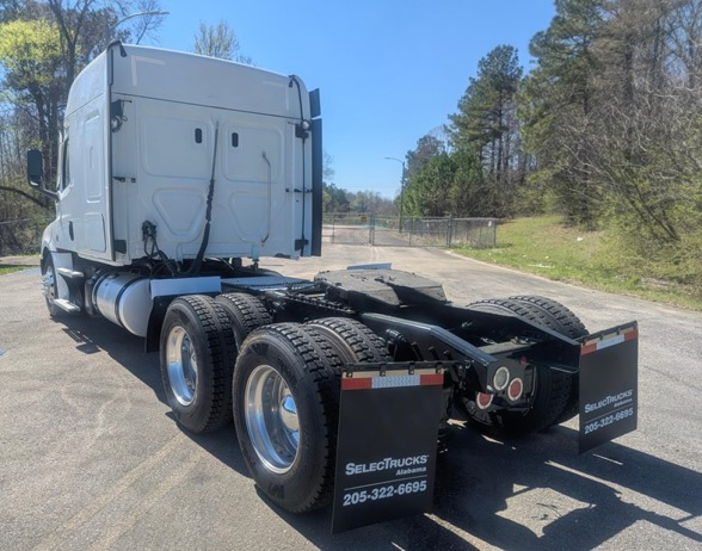 Freightliner Cascadia 126 tractor rear view showing dual rear axles and mudflaps with SelectTrucks Alabama contact text.