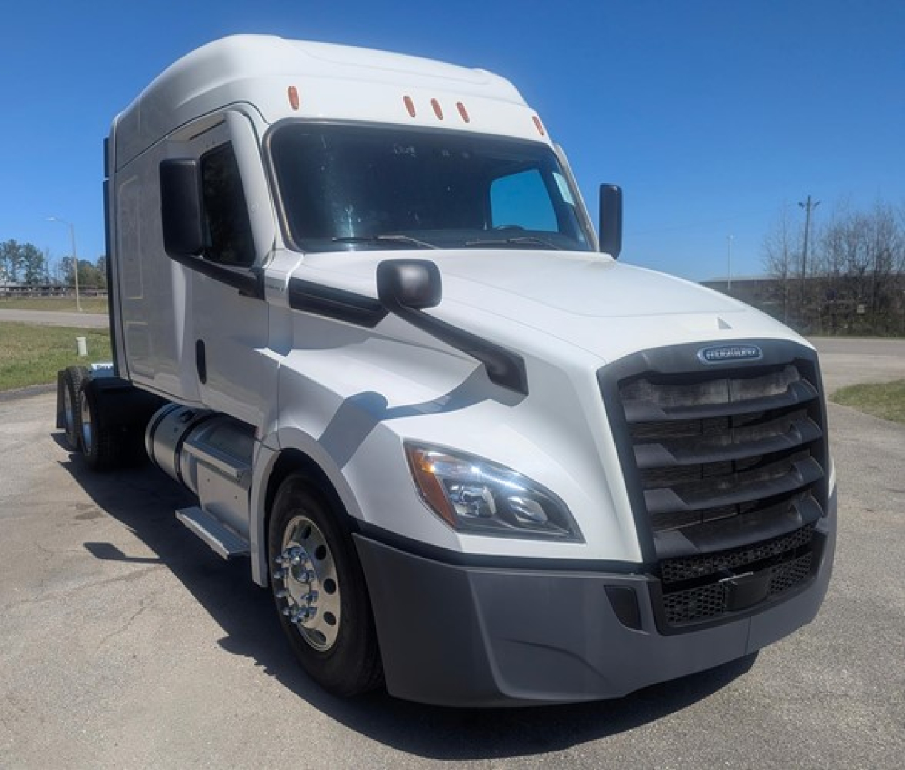 Freightliner Cascadia 126 sleeper tractor in white, front-left view, with black grille and mirrors, daytime outdoor lot.