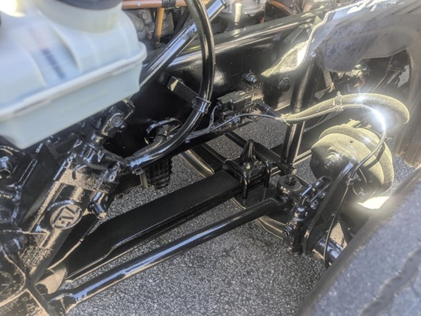 Freightliner Cascadia chassis view showing front axle and steering linkage with hydraulic lines and frame rails.
