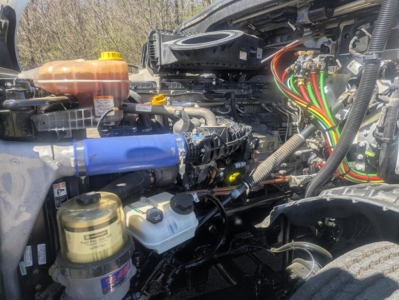 Freightliner Cascadia 126 engine bay with visible hoses, wiring, coolant reservoir, and filter canister.