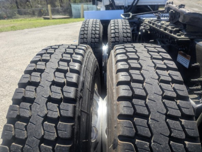Tractor-trailer tandem dual tires on Freightliner Cascadia 126 showing heavy tread blocks and wheel alignment.