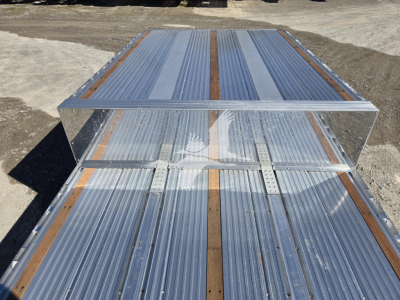 All-metal dropdeck trailer deck with polished aluminum and wood planks, showing a raised frame and side channels.