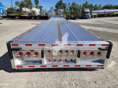 Trailer rear view showing chrome polished deck with multiple vertical and round taillight housings and reflective tape along edges.