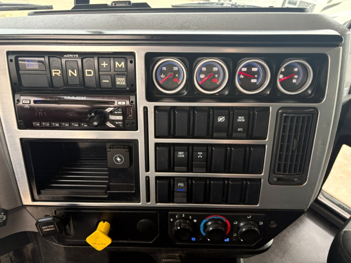 Cab dashboard of a 2020 Mack GR64F showing instrument gauges, radio, climate controls, and various switches.