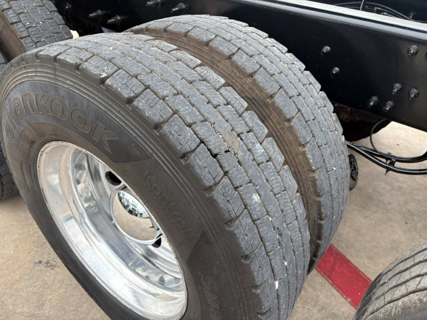 Hankook dual rear tires on a Mack GR64F dump truck, chrome wheel rims, frame and suspension visible with tire treads and sidewall text Hankook.