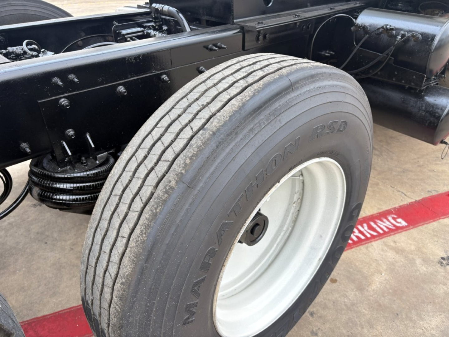 Mack GR64F dump truck chassis showing front tire and wheel with NF Northland radial tire markings and chassis frame components.