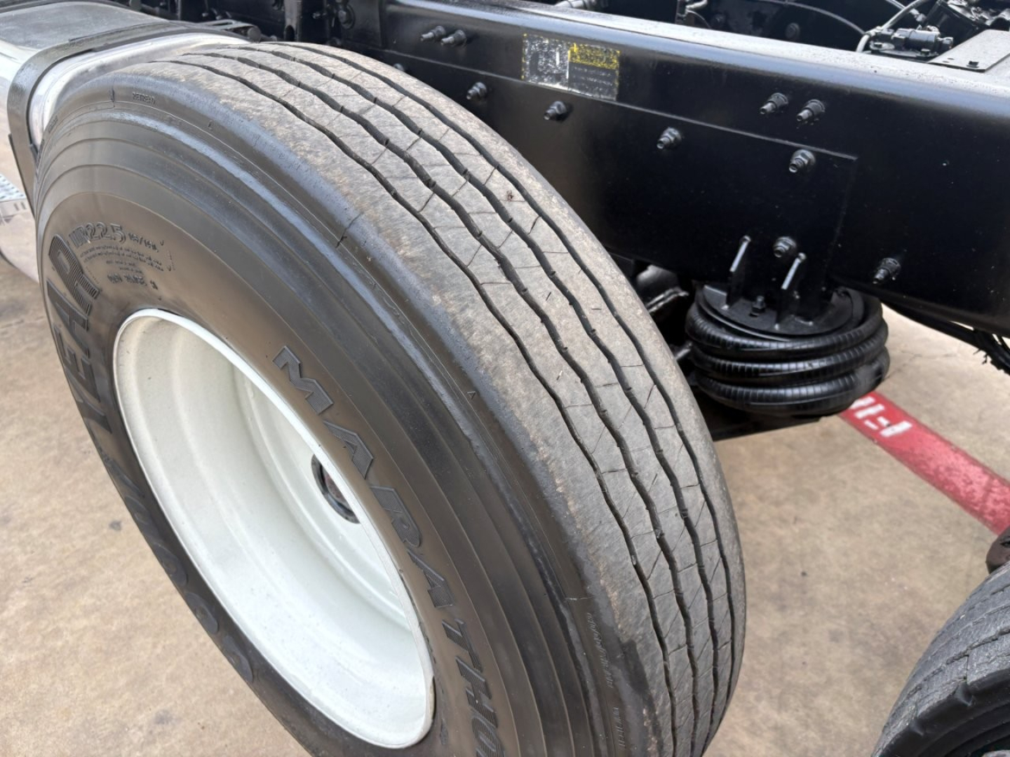Mack GR64F dump truck front wheel showing tire sidewall and suspension components.