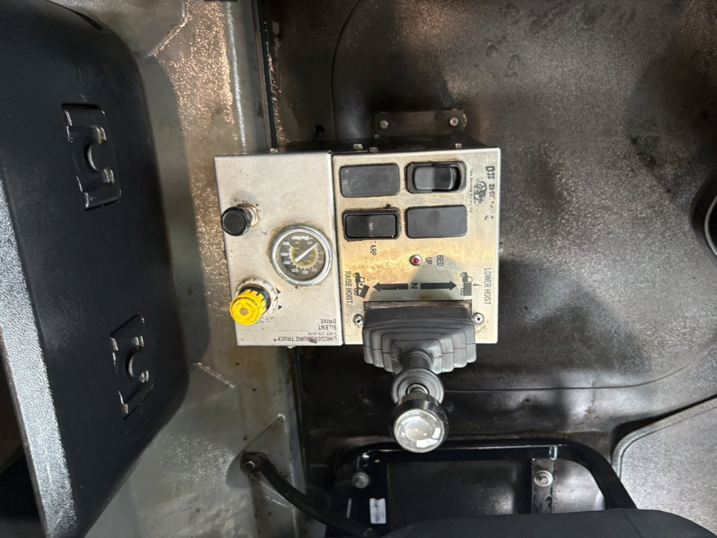 Panel with gauge and control levers inside Mack GR64F cab showing pressure gauge, yellow knob, and digital display module.