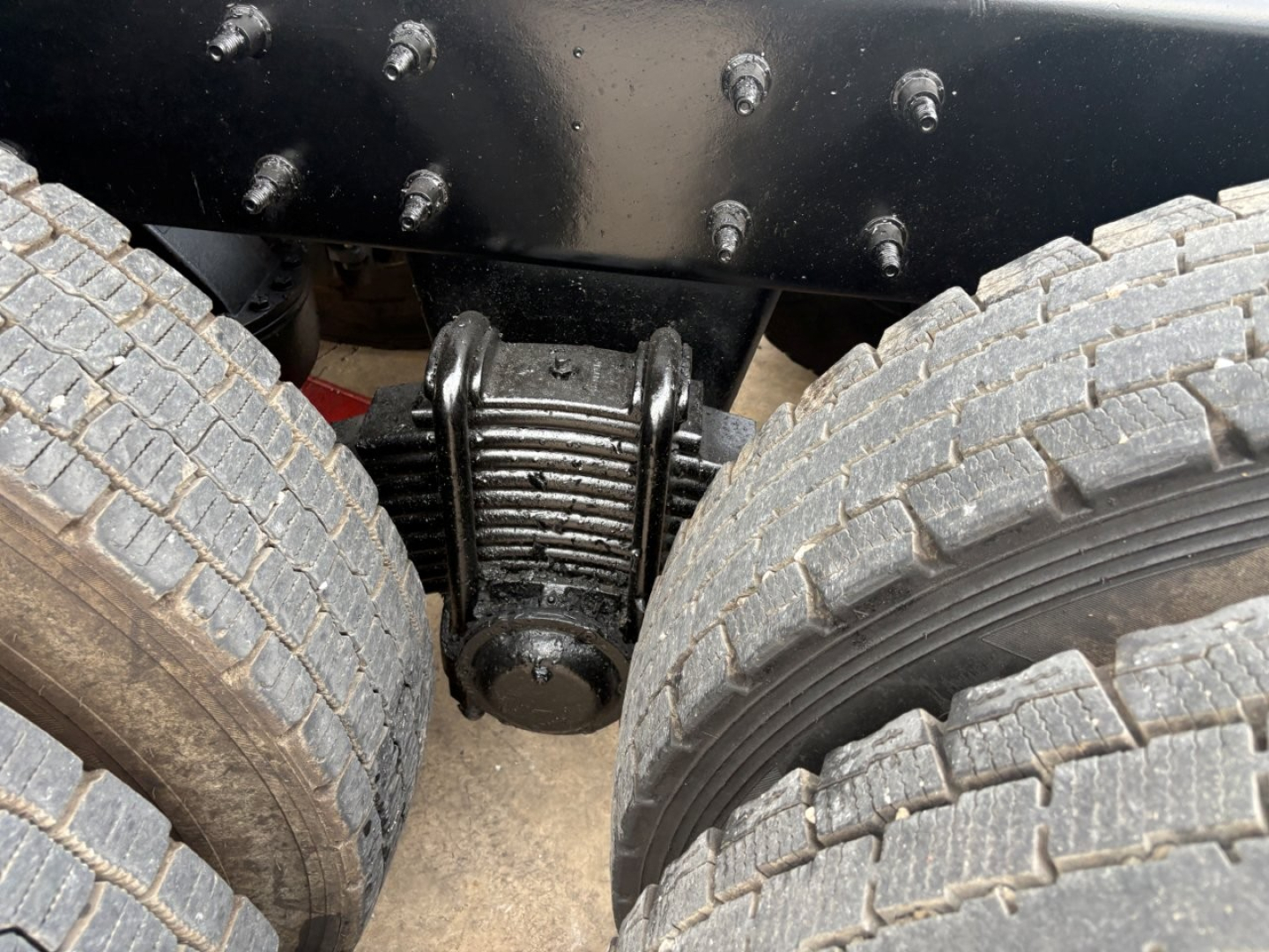Mack GR64F truck rear dual rear axle suspension with leaf springs and heavy duty airbags, chrome bolts, engine bay area not visible.