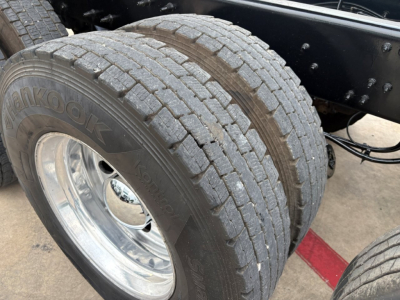 Hankook dual rear tires on a Mack GR64F dump truck, chrome wheel rims, frame and suspension visible with tire treads and sidewall text Hankook.