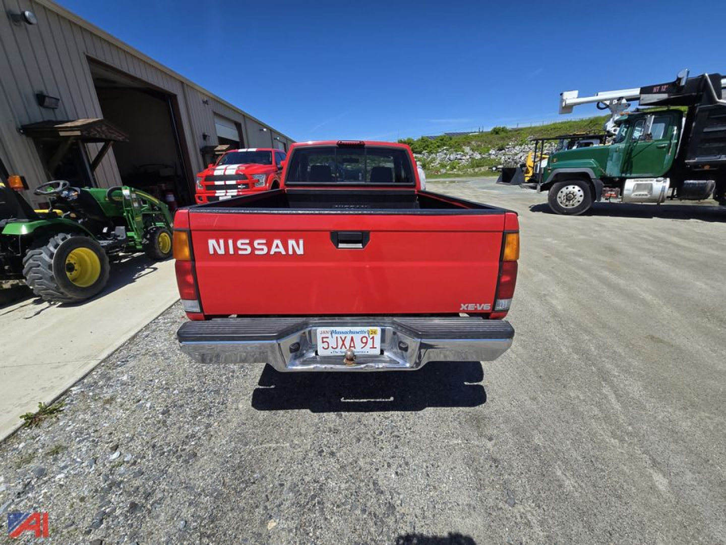 Red 1995 Nissan pickup truck rear view showing NISSAN on tailgate and California license plate 5JXA91 in a industrial yard.