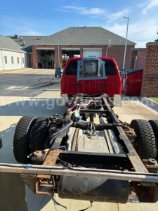 Rear view of a red Ford F-550 cab and chassis showing chassis frame and dual rear axle.