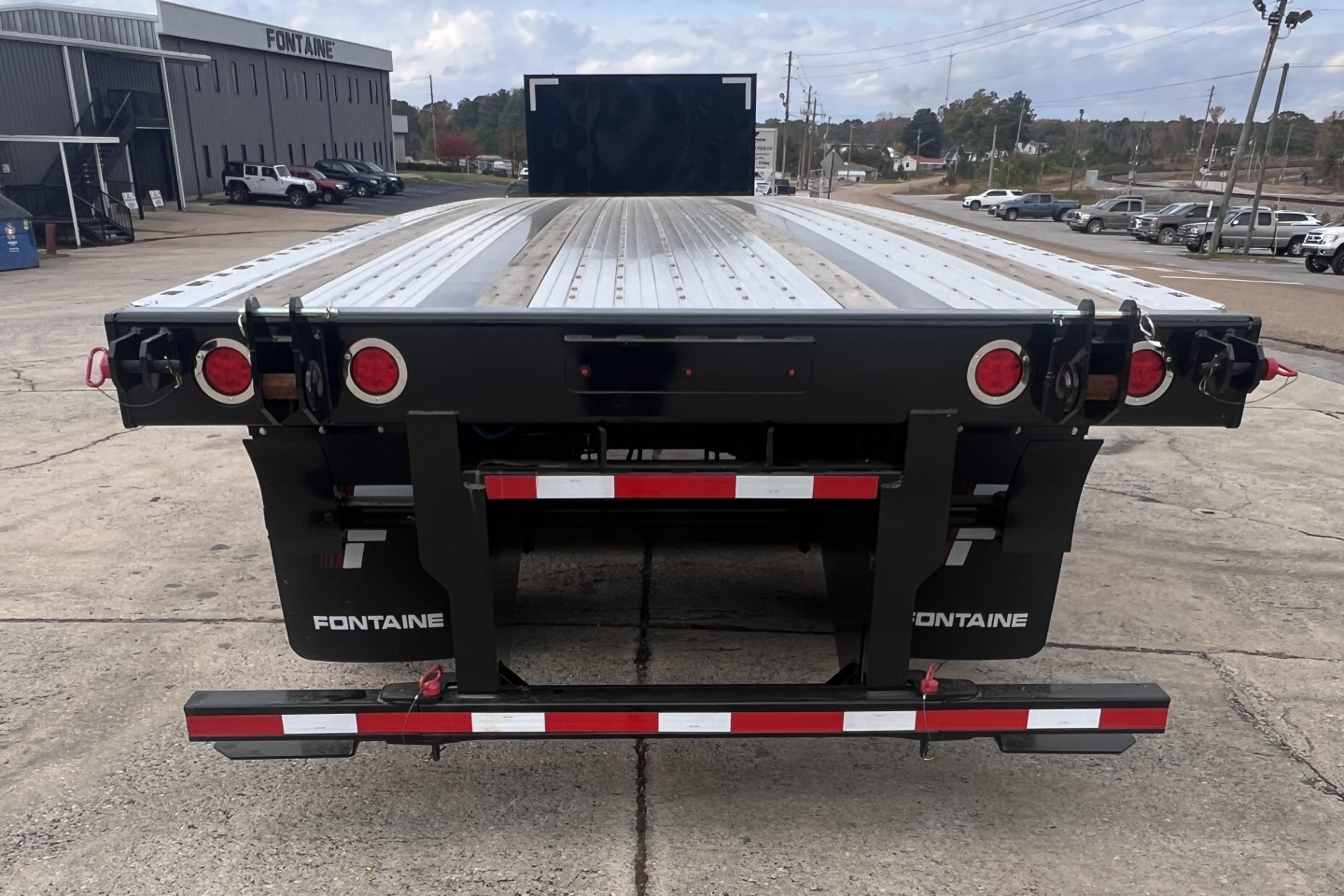 Flatbed trailer rear view showing Fontaine branding, taillights, and rear lift components with a flat aluminum deck.