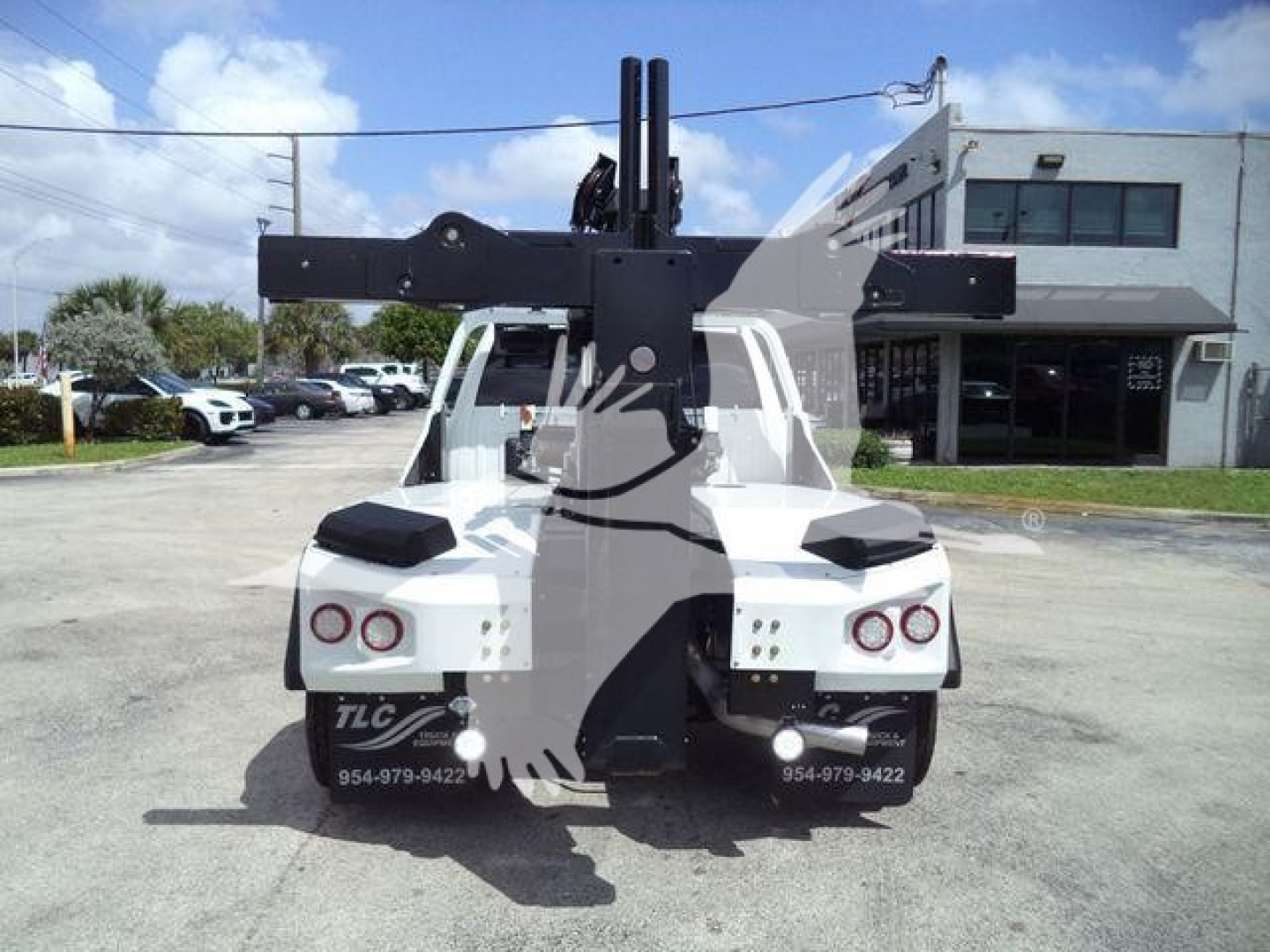 Ram 5500 tow rig with large front hitch/boom seen from rear; visible text shows TLC and contact numbers on rear fenders.