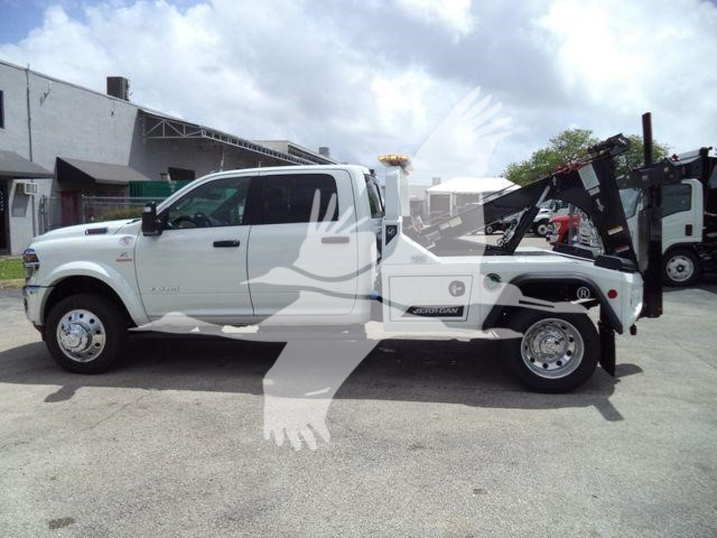 Ram 5500 tow truck side view showing white crew cab and tow equipment in the bed.