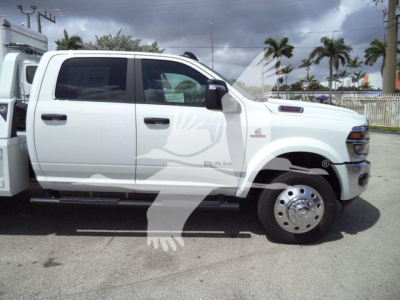 Ram 5500 Big Horn pickup truck side view showing white cab and wheel with chrome hubcap, winch equipment on bed, black mirrors, running boards.