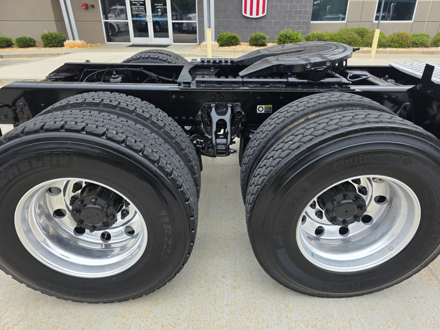 Kenworth T880 rear wheels and chassis showing dual rear tires and fifth wheel mounting area with black frame and chrome wheels.