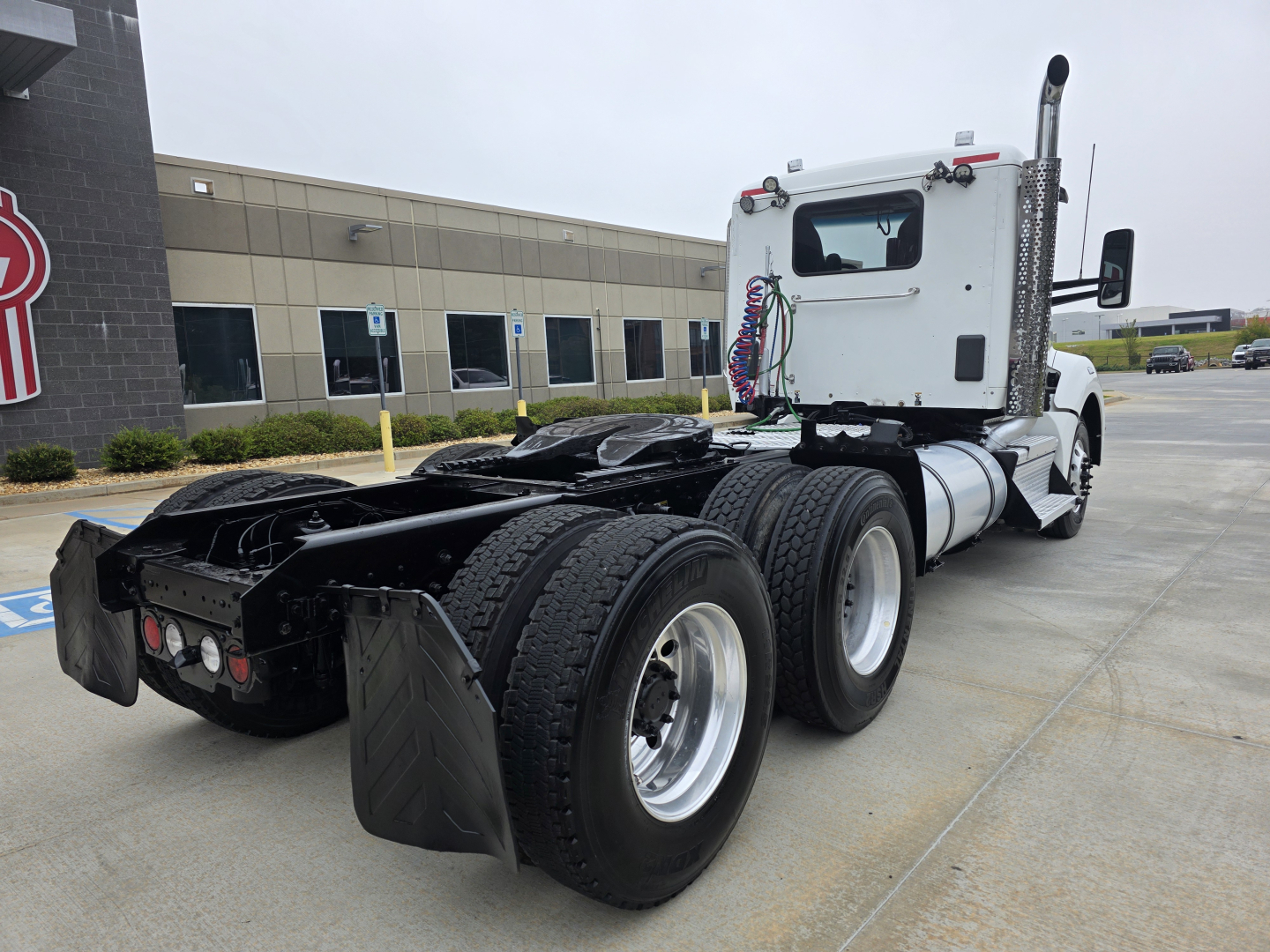 Kenworth T880 tractor rear view showing dual rear axles with attached fifth wheel, exhaust stack, and hoses.