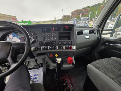 Kenworth T880 cab interior showing steering wheel, instrument cluster, center console with gauges, and gear shifter.