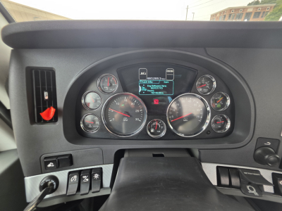 Kenworth T880 truck dashboard with multiple gauges and center display panel showing trip information.