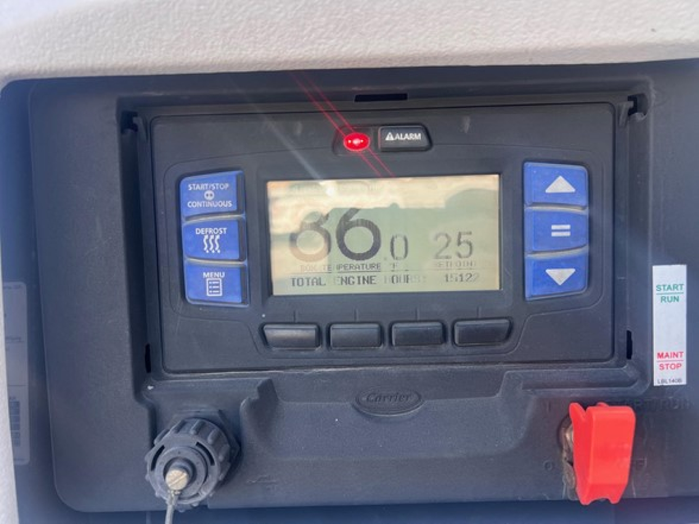 Reefer trailer control panel with digital display showing 68 and 25, buttons on sides, red emergency switch, and control dials.