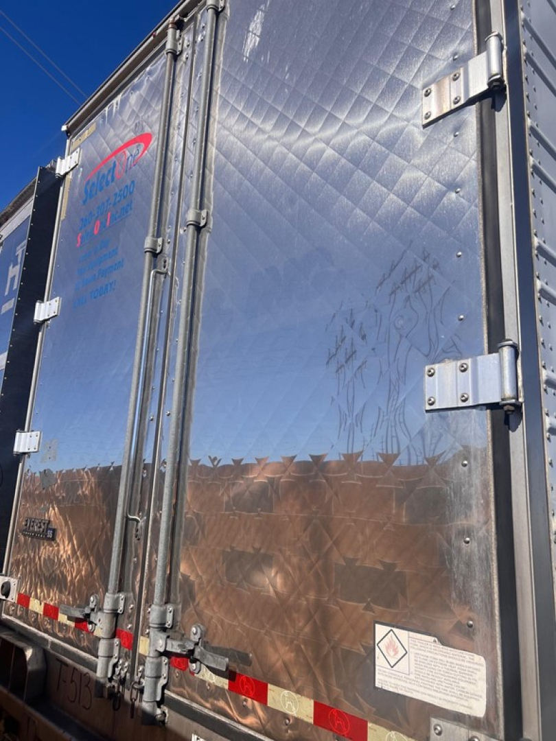 Rear doors of a 2015 Great Dane air ride reefer trailer with diamond plate metal, hinges, latches, warning sticker, and blue/purple logo partially visible.