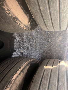 Trailer wheel well view showing dual tires with dirt and gravel on ground between tires; focus on tread patterns and inner dual wheels of a Great Dane air ride reefer.