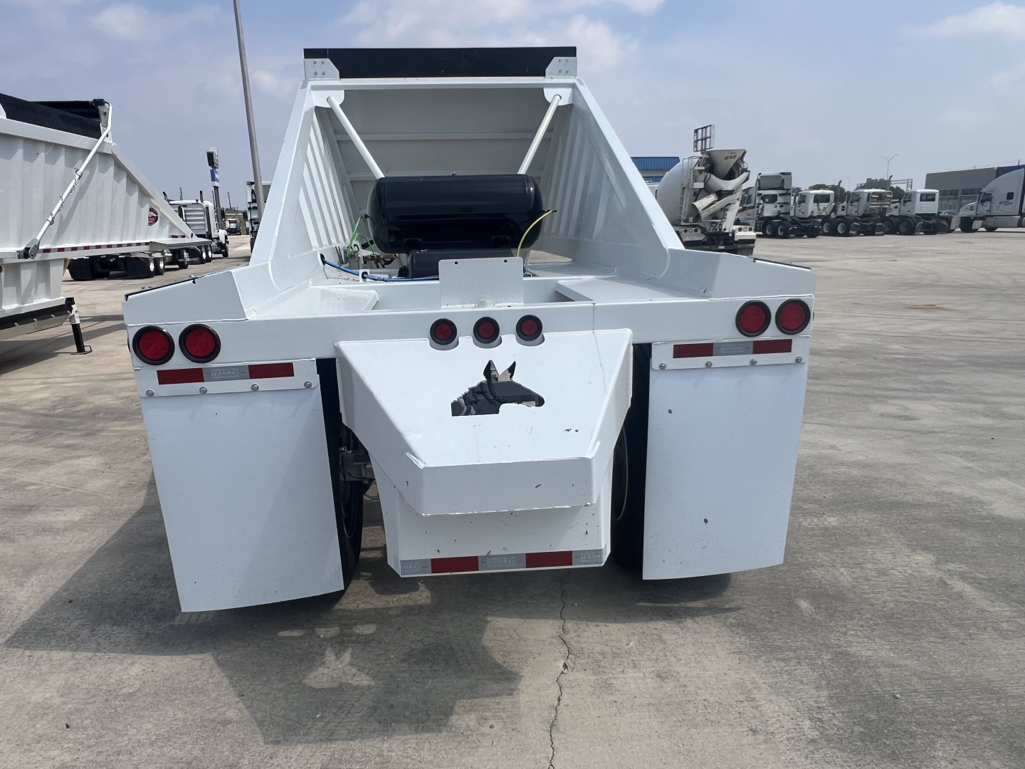 Dump trailer rear view showing hydraulic air ride system with white steel body and taillights, no slip shaft text visible.