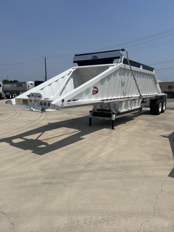 Dump trailer showing white CTS BDT-40 air ride bed with dual axles and hydraulic components.
