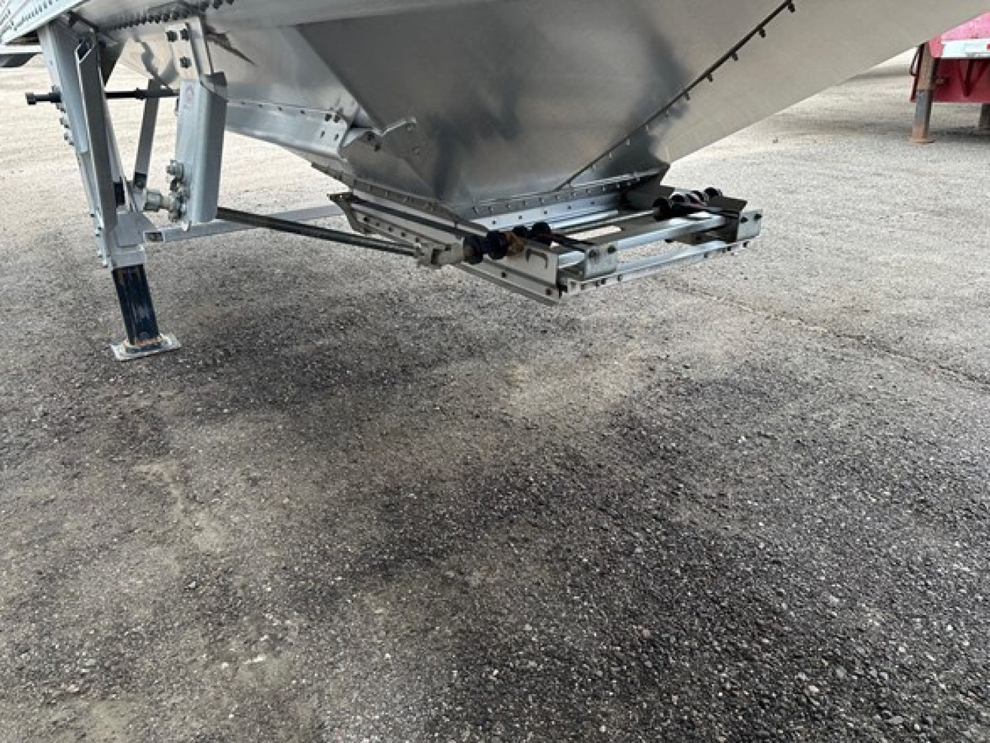 Trailer hitch underside of a Timpte Super Hopper 66" side showing support legs and hitch mechanism with metal frame and gravel surface.