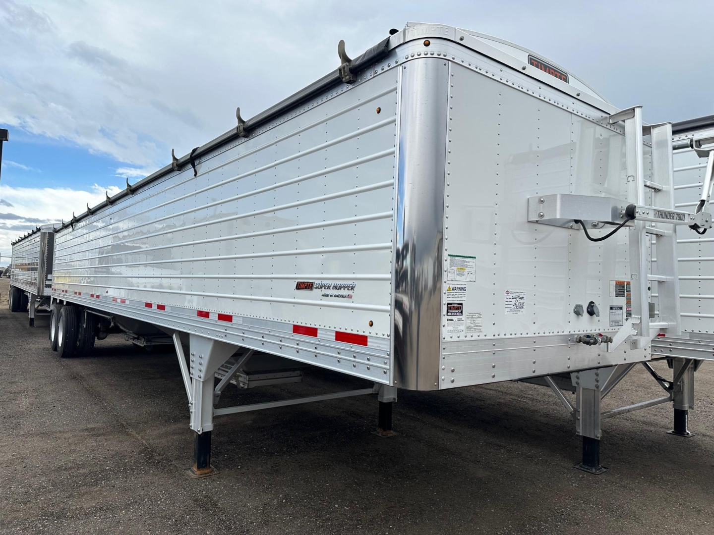 Trailer side view showing Timpte Super Hopper W 66" side with aluminum structure, dual-axle, hitch on front right, loading chute, and reflective strips.