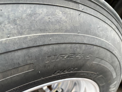 Trailer tire with visible lettering: 11R22.5 size and other markings on sidewall; some dirt and grime on the tire surface.