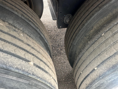 Trailer axle pair with dual tires and hub area visible under hopper trailer side.